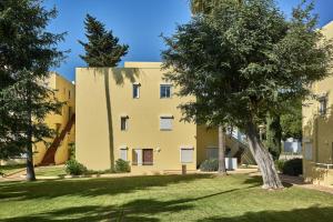 a yellow building with trees in front of it at Parque Mourabel, Oásis Village & Pé do Lago in Vilamoura