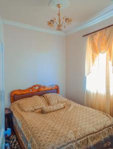 1 dormitorio con 1 cama con lámpara de araña y ventana en Aspet B&B, en Tatʼev