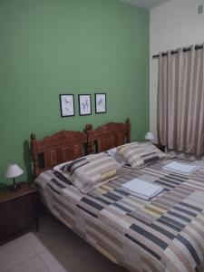 サンタ・バルバラにあるPousada Capão da Corujaのベッドルーム1室(大型ベッド1台付)が備わります。壁には2枚の写真が飾られています。