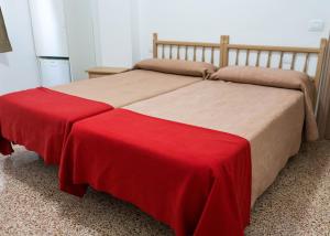 a bedroom with two beds with a red blanket at Pensión Alcalá in Alcalá