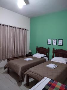 2 łóżka w pokoju z zielonymi ścianami w obiekcie Pousada Capão da Coruja w mieście Santa Bárbara d’Oeste