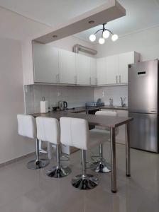 a kitchen with a wooden table and white chairs at Loutraki vibes apartments in Loutraki
