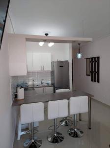 a kitchen with a counter and some white chairs at Loutraki vibes apartments in Loutraki