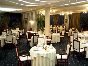 a dining room with white tables and chairs at Mirage Hotel in Burgas City