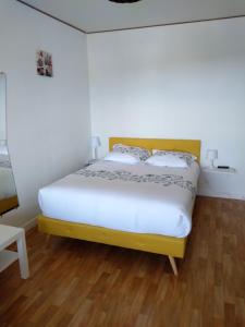 Łóżko w pokoju z drewnianą podłogą w obiekcie Résidence La Jamoisiére w mieście Bagnoles de l'Orne
