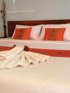 two beds with white sheets and orange pillows at Vacation House in Klong Muang Beach