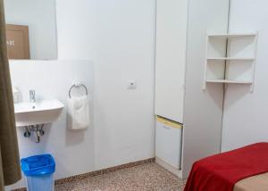 a small white bathroom with a sink and a bed at Pensión Alcalá in Alcalá