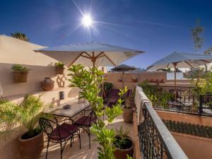 een balkon met een tafel, stoelen en parasols bij Riad Oumnia - Top emplacement - Riad en entier pour vous in Marrakesh