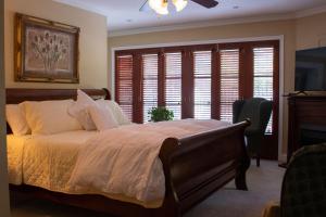 a bedroom with a bed with white sheets and windows at Upper Canada Coach House in Niagara on the Lake