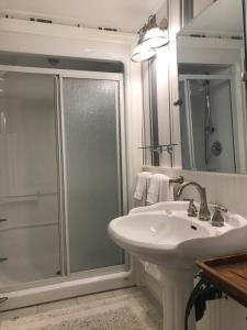 a white bathroom with a shower and a sink at Upper Canada Coach House in Niagara on the Lake