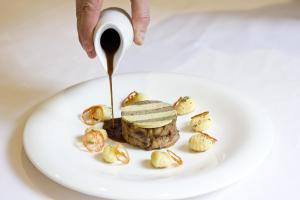 a person drizzling sauce onto a plate of food at Relais & Châteaux Hotel Orfila in Madrid