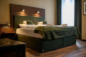 a bedroom with a large bed with a green headboard at Stadthotel König Albert in Zittau