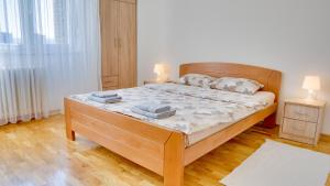 a bedroom with a wooden bed with two lamps on it at MILICA 65m2, Free parking & Wi-fi in Novi Sad