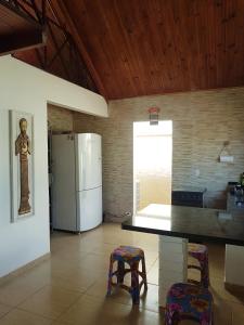 eine Küche mit einem Kühlschrank und 2 Hockern in der Unterkunft Casa Toá, Chapad dos Veadeiros in Alto Paraíso de Goiás