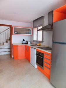 een keuken met oranje en witte kasten en apparaten bij Chalet amplio con Jardín y zona barbacoa. in Reus
