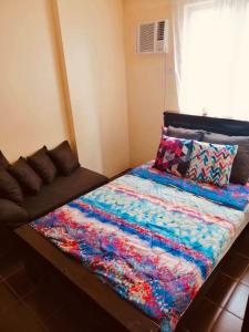 a bed with a colorful blanket on top of it at The Rochester Parklane Condominium in Manila