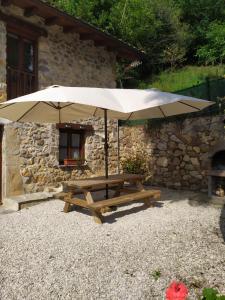 Casa Adela El Tuxu في Perlleces: طاولة نزهة مع مظلة أمام المبنى
