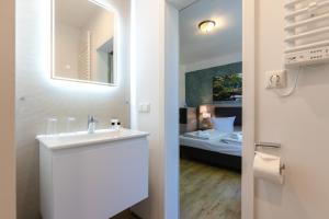 a bathroom with a sink and a room with a bed at Landhotel Gutshof im Oertzetal in Oldendorf, Südheide in Hermannsburg