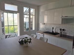 a white kitchen with a table and some chairs at Belle Maison 12p 6 couchages TOURS CENTRE avec jardin in Tours