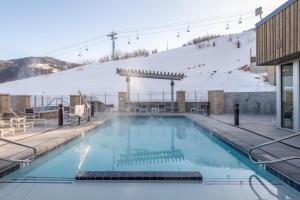 uma piscina com montanhas cobertas de neve ao fundo em Elevated Living Slopeside Mountain Luxury 5 Bedroom Private Hot Tub Ski In Ski Out End Unit Townhome em Park City