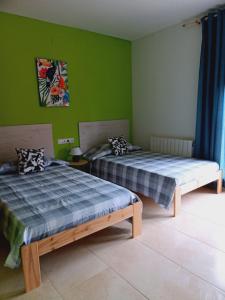 2 camas en una habitación con paredes verdes en Chalet amplio con Jardín y zona barbacoa. en Reus