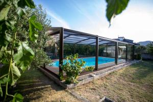 uma casa de vidro com piscina num quintal em Villa Albino Piscina climatizada 