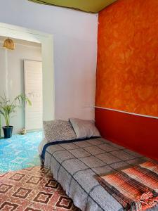 Cama en habitación con pared de color naranja en Hostal Posada Mi Casa en San Cristóbal de Las Casas
