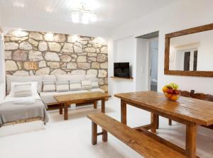 a living room with a table and a stone wall at Villa DORIANA IN PELEKOUDA in Pollonia