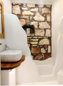 a bathroom with a sink and a stone fireplace at Villa DORIANA IN PELEKOUDA in Pollonia