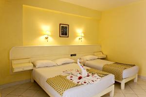 two beds in a room with yellow walls at Empire Hotel Aqua Park - Couples and Families in Hurghada +41 photos