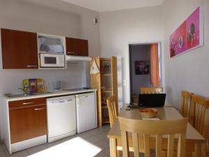 uma cozinha com uma mesa e um frigorífico branco em Appartement bord de plage Tranche s/mer em La Tranche-sur-Mer