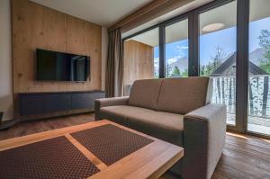 a living room with a couch and a table and a tv at Apartmány a Chalety Horizont Resort in Stará Lesná