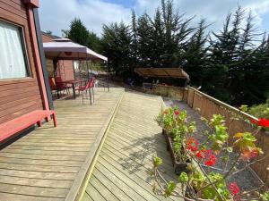 a wooden deck with a table and chairs and flowers at Cabaña Girasol - Cocina Parking Piscina Wifi in Algarrobito