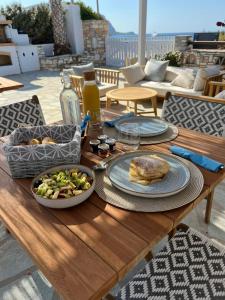 a wooden table with plates of food and a salad at KAMEO, Antiparos in Antiparos