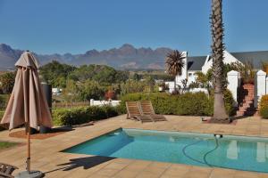 a swimming pool with two chairs and a umbrella at Wild Mushroom Country House in Stellenbosch