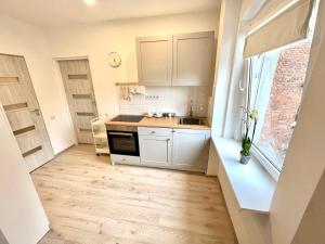 a kitchen with white cabinets and a sink and a window at New York Apartments in Katowice