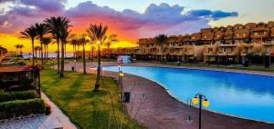 a resort pool with palm trees and a sunset at Stella Di Mare Sea View - Amazing Two Bedrooms Standalone Cozy Villa - Families only in Ain Sokhna