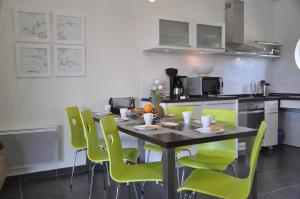 a kitchen with a table and green chairs at Villas Blue Idea in Ploumoguer