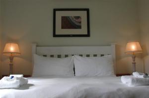a bed with two towels on it with two lamps at D'Aria Guest Cottages in Durbanville