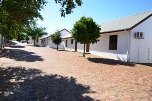a brick road in front of a white building at D'Aria Guest Cottages in Durbanville