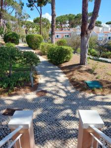 zwei weiße Bänke auf einem Bürgersteig in einem Park in der Unterkunft Quinta do Lago Golf, Sea & Sun in Quinta do Lago