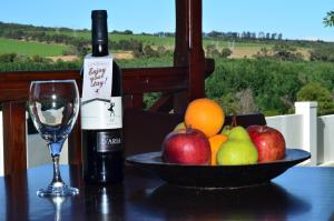 a bottle of wine and a bowl of fruit on a table at D'Aria Guest Cottages in Durbanville