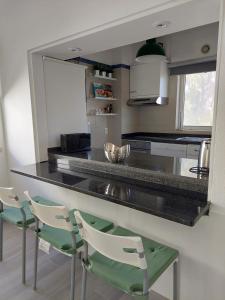 una cocina con 2 sillas blancas y una barra en Quinta do Lago Golf, Sea & Sun, en Quinta do Lago