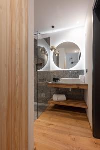 a bathroom with a sink and a mirror at Alpuris - Your Boutique Suite - Hotel B&B in Cavalese