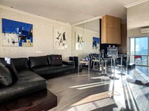 a living room with a black couch and a kitchen at Splice Apartments in Johannesburg