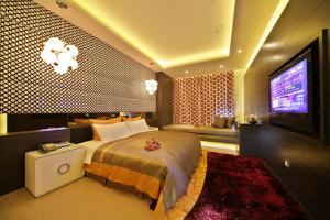 una camera con un grande letto e una TV a schermo piatto di Han Guan Motel a Taichung