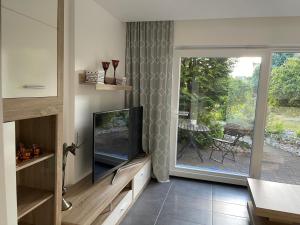 een woonkamer met een tv en een glazen schuifdeur bij Ruhige Ferienwohnung in der Stadtmitte in Hadamar
