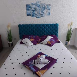 a bed with a blue headboard and pillows on it at Apartman u centru 1 in Šid