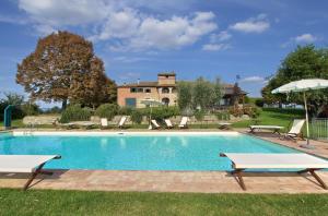 a swimming pool with chairs and a house in the background at Villa Borgonuovo in Cortona