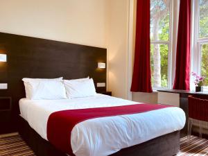 a bedroom with a large bed with red curtains at Piccadilly Hotel in Bournemouth